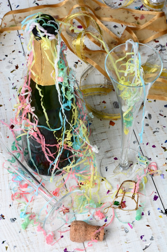 高角拍摄香槟瓶飘带而且五彩纸屑后新年夏娃聚会，派对垂直格式与浅深度场焦点的前景而且表格前