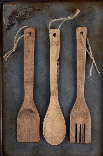 高角拍摄三个木厨房餐具叉勺子而且抹刀与线通过的处理洞使用金属烘焙表垂直格式