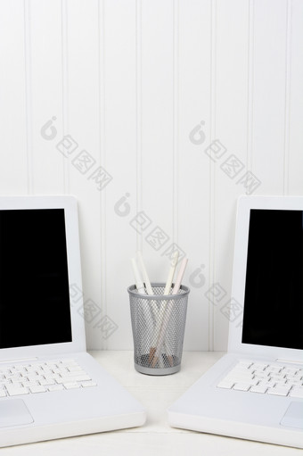 特写镜头两个笔记本电脑白色工作站与铅笔杯的中间的电脑是角与空白屏幕而且复制空间以上垂直格式