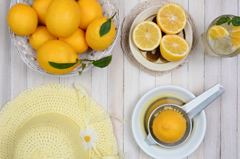 使柠檬水仍然生活拍摄从高角乡村白色木厨房表格与柠檬榨汁机黄色的阀盖而且玻璃柠檬水