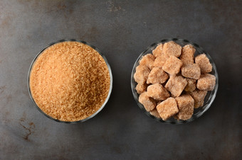 两个碗棕色（的）糖一个碗粒状生turbinado糖而且第二个碗自然棕色（的）糖肿块高角视图使用金属烘焙表