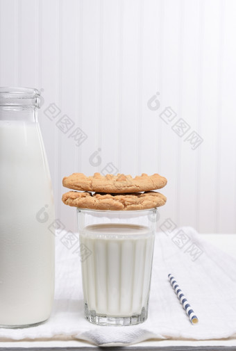 牛奶和饼干零食白色表格与白色墙饼干是堆放的玻璃牛奶