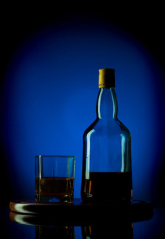 威士忌瓶而且玻璃木托盘蓝色的背景