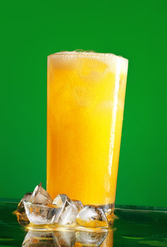 玻璃橙色苏打水与冰在绿色背景