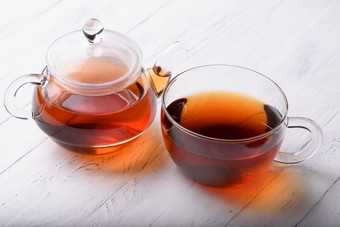 玻璃<strong>茶壶</strong>和杯与热黑色的茶白色木表格