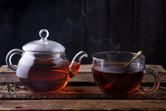 热茶玻璃<strong>茶壶</strong>和杯与勺子和蒸汽木表格黑暗仍然生活
