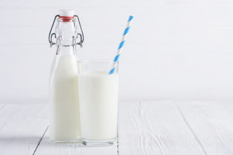 玻璃牛奶与纸稻草和牛<strong>奶瓶</strong>木白色表格仍然生活