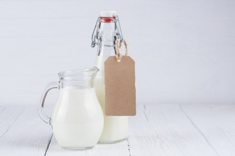 瓶牛奶和Jar牛奶与空白纸板标签白色木表格背景