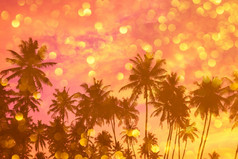 tropiocal海滩日落与棕榈树轮廓和金闪亮的散景双曝光效果