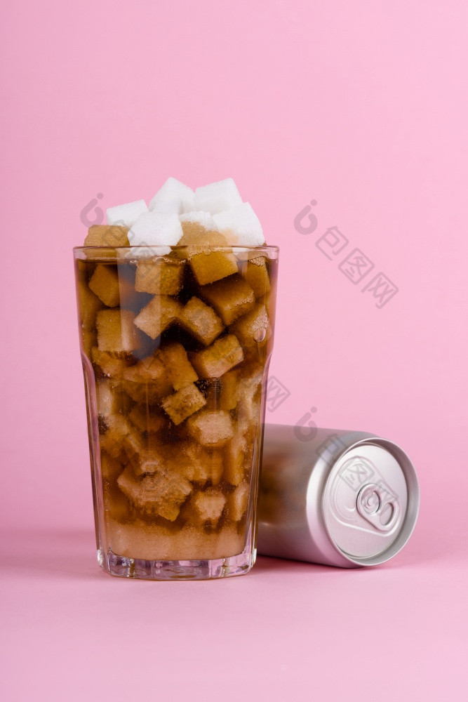 玻璃肿块糖多维数据集和软尾巴喝与铝可以粉红色的柔和的背景不良的饮食与甜蜜的含糖的软饮料概念