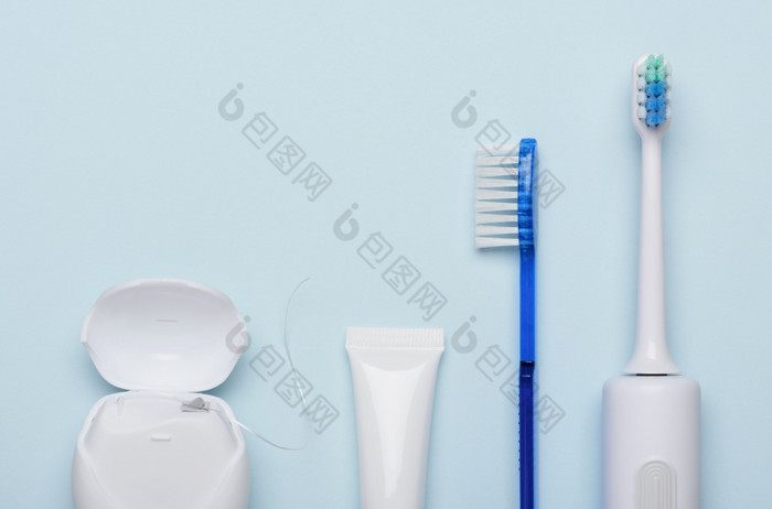 电声波牙刷与牙科牙线牙膏和经典牙刷蓝色的背景平躺
