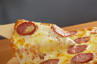 自制的披萨意大利辣香肠采取片披萨融化了奶酪滴
