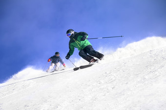 两个滑雪者滑雪下坡高山而且阳光明媚的一天