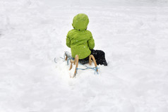 孩子绿色夹克享受雪橇骑雪冬天公园