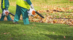 工人清洁下降秋天叶子与叶鼓风机
