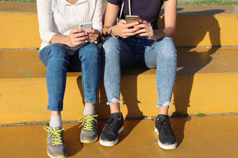 两个年轻的女孩看聪明的<strong>移动手机</strong>