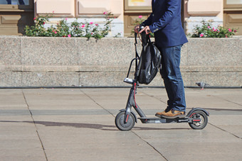 男人。骑踢踏板车的城市广场
