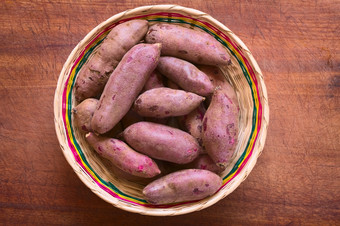 开销拍摄生紫色的甜蜜的土豆年番薯拉编织篮子木董事会拍摄与自然光
