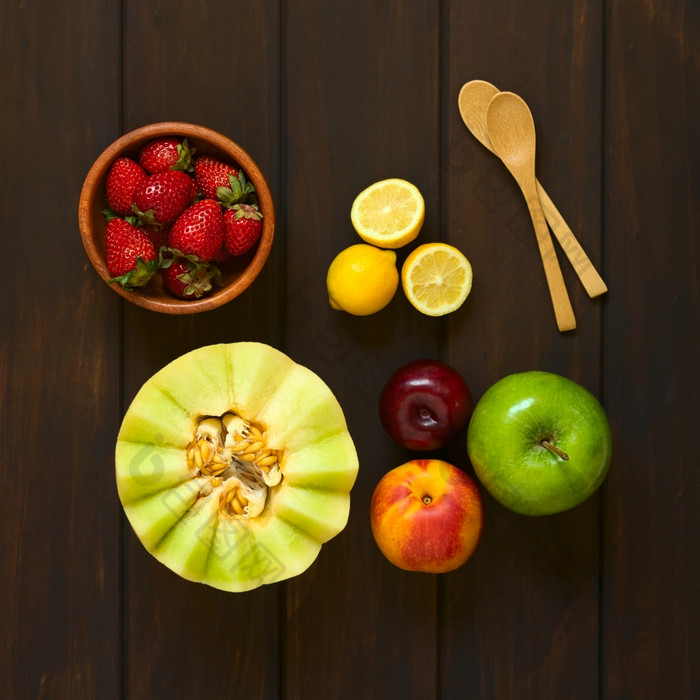 开销拍摄各种新鲜的水果蜜汁瓜高丽油桃苹果草莓李子柠檬与小木勺子的一边拍摄黑暗木与自然光