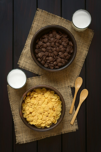 脆皮巧克力而且简单的玉米片早餐麦片乡村碗与眼镜牛奶而且木勺子的一边拍摄开销黑暗木与自然光