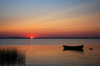 孤独的划艇平静水日落与的奥兰桥瑞典背景