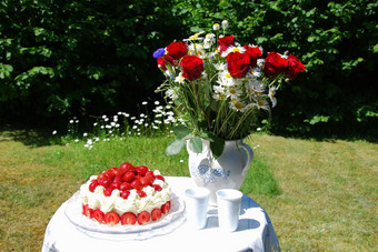 表格集为夏天庆祝活动在户外与草莓蛋糕和花束夏天花