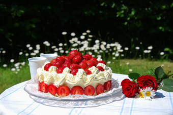 夏季与草莓蛋糕和两个杯子表格花园
