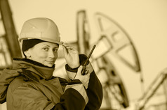 女工人的石油场会说话的的广播穿红色的头盔和蓝色的工作衣服工业网站backgroundtoned乌贼