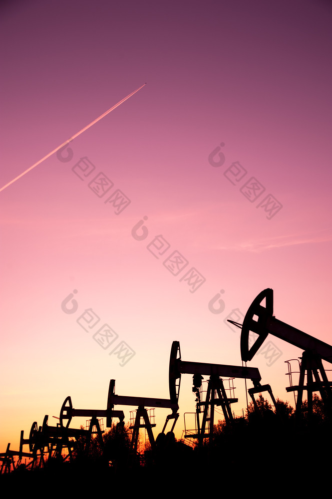 石油泵杰克油田和飞机航迹云日落天空背景概念石油和气体行业石油泵和飞机