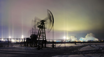 石油和气体行业全景泵头油田和石油炼油厂的冬天天空背景与光支柱效果晚上视图石油概念冬天晚上视图泵杰克提取石油