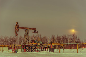石油泵杰克油田冬天日落天空背景提取石油石油概念健美的泵杰克提取石油石油概念