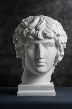 白色石膏复制古老的雕像安提诺乌斯头为艺术家黑暗变形背景石膏雕塑男人。脸石膏复制古老的雕像安提诺乌斯头黑暗变形背景石膏雕塑男人。脸