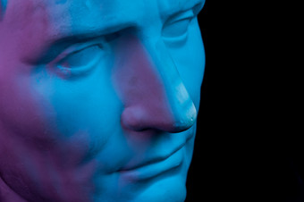 健美的石膏复制古老的雕像的家伙朱利叶斯凯撒屋大维八月头为艺术家黑色的背景石膏雕塑男人。脸蓝色的和粉红色的健美的石膏复制古老的雕像八月头孤立的黑色的背景石膏雕塑男人。脸