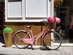 这古董粉红色的女孩自行车有美丽的粉红色的花篮子的前面的自行车