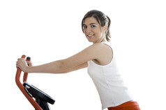 年轻的女人培训锻炼自行车的健身房