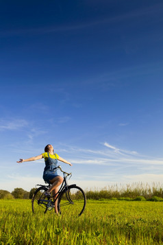 快乐女孩在自行车和看的视图绿色草地