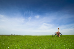 快乐年轻的女人与古董自行车绿色草地