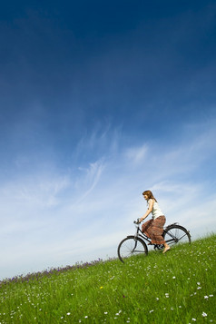 快乐年轻的女人绿色草地骑自行车