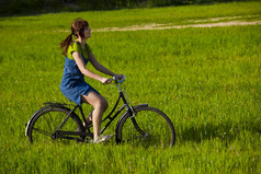快乐年轻的女人绿色草地骑自行车