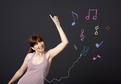 年轻的女人跳舞和听音乐与音乐的笔记画与粉笔黑色的墙