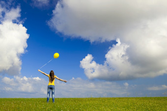 快乐年轻的女人与黄色的气球绿色草地