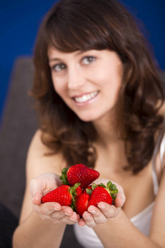 美丽的和快乐年轻的女人与手完整的草莓