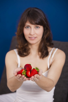 美丽的和快乐年轻的女人持有草莓与这两个手