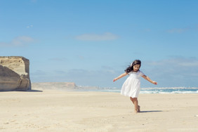 小女孩跳舞的海滩与衣服