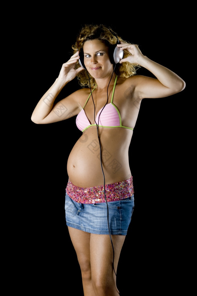 美丽的和年轻的怀孕了女人听音乐一点点头手机