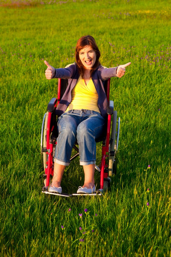 快乐<strong>残疾</strong>女人与拇指坐着轮椅在绿色草地