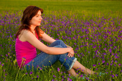 美丽的年轻的女人坐着华丽的草地