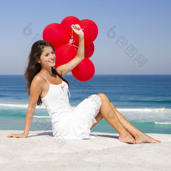 美丽的女孩与红色的<strong>气球坐</strong>着的海滩