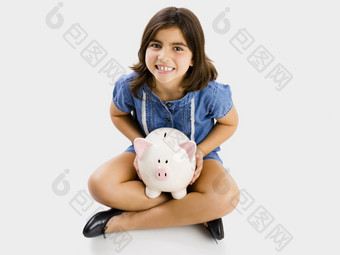 年轻的女孩坐着地板上和持有存钱罐