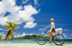 女人自行车骑沿着的海滩塞舌尔